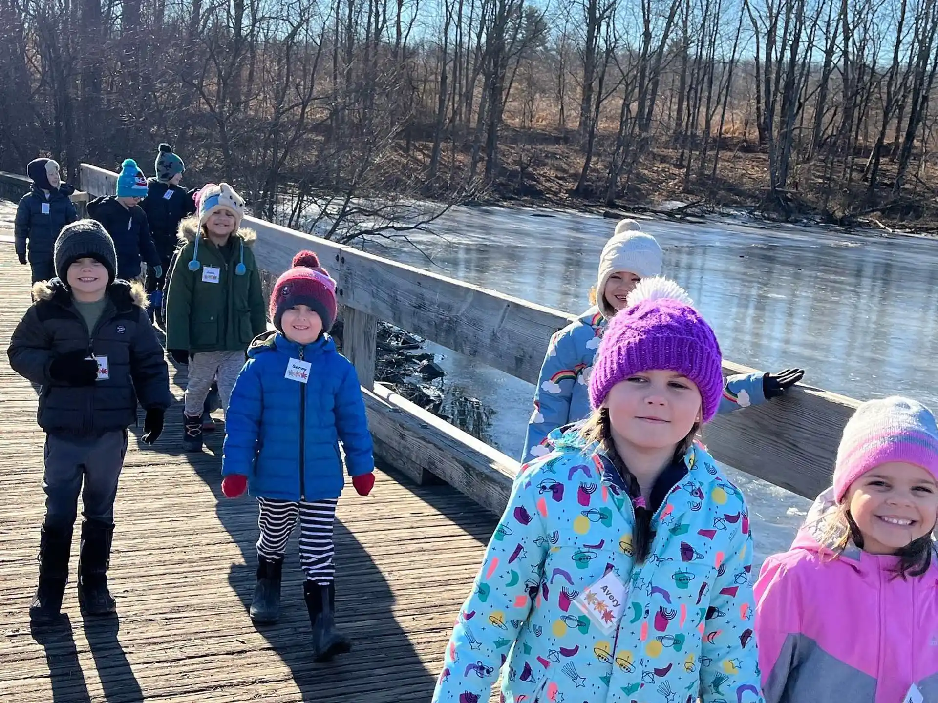 a group of children walking on a path by a river
