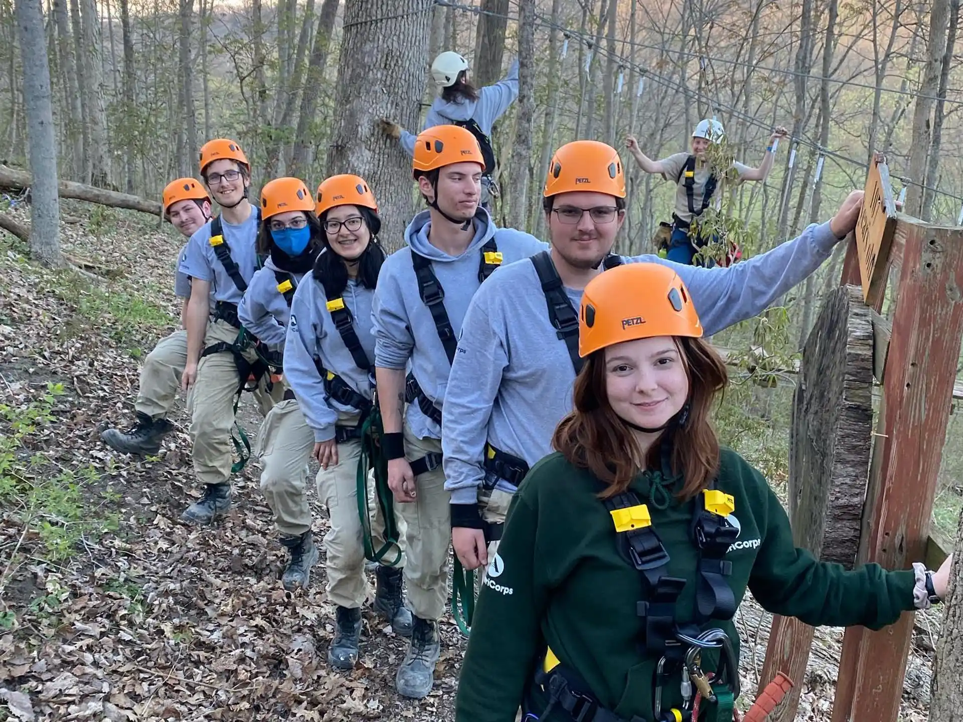 a group of people wearing helmets and standing in a forest