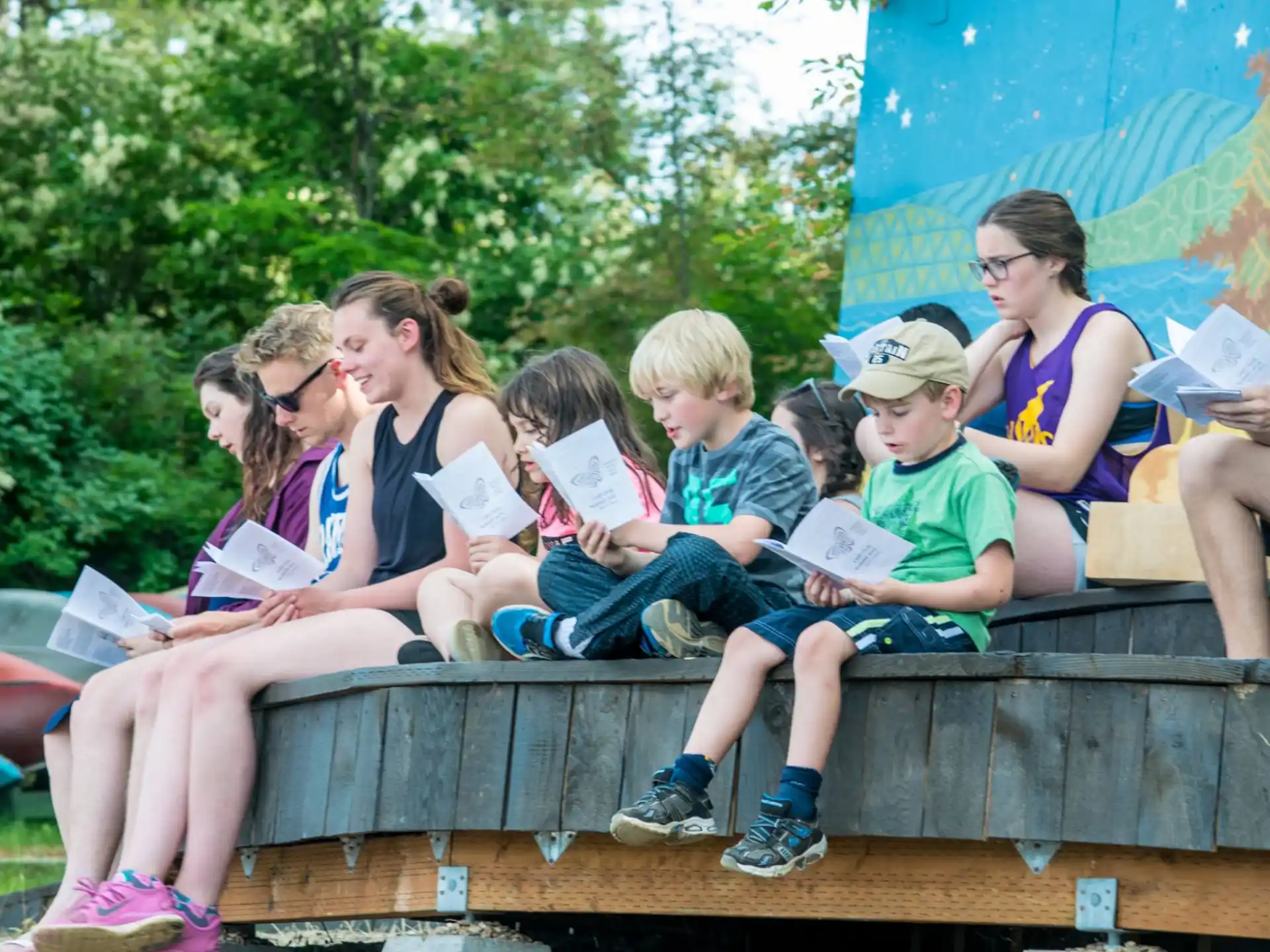 a group of children sitting on a bench reading books