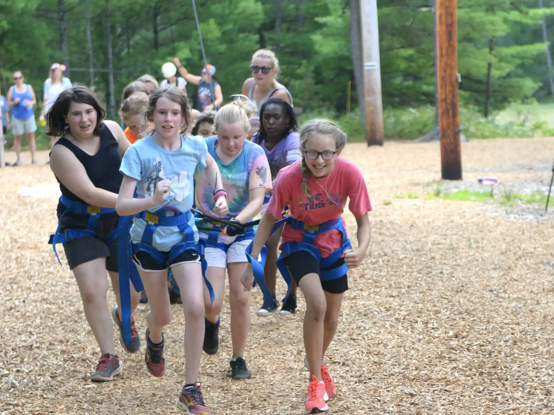 a group of people running on a dirt path in the woods