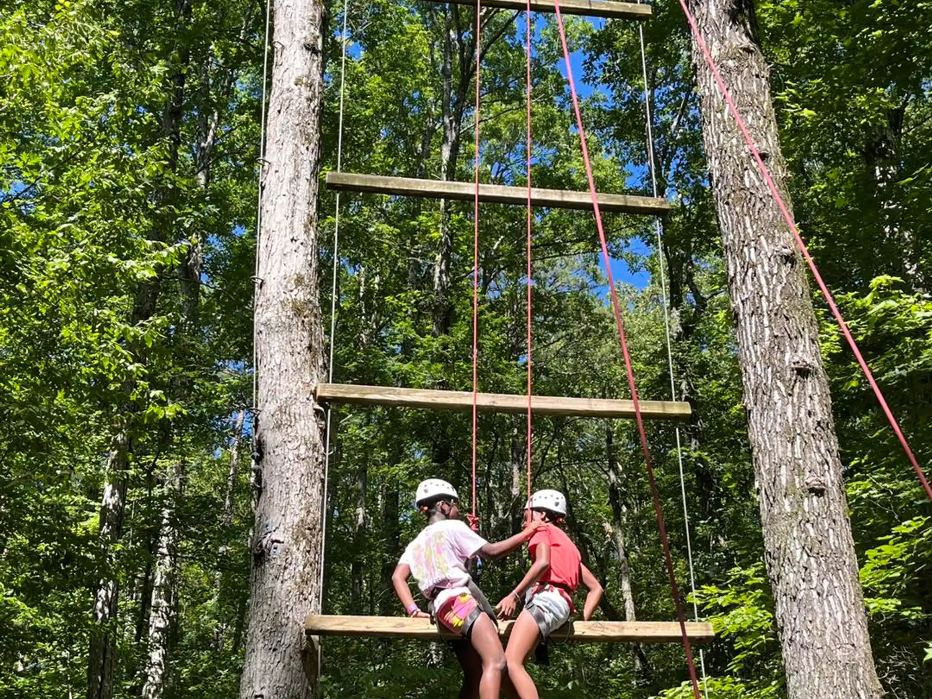 a couple of people sitting on a wooden structure in the woods