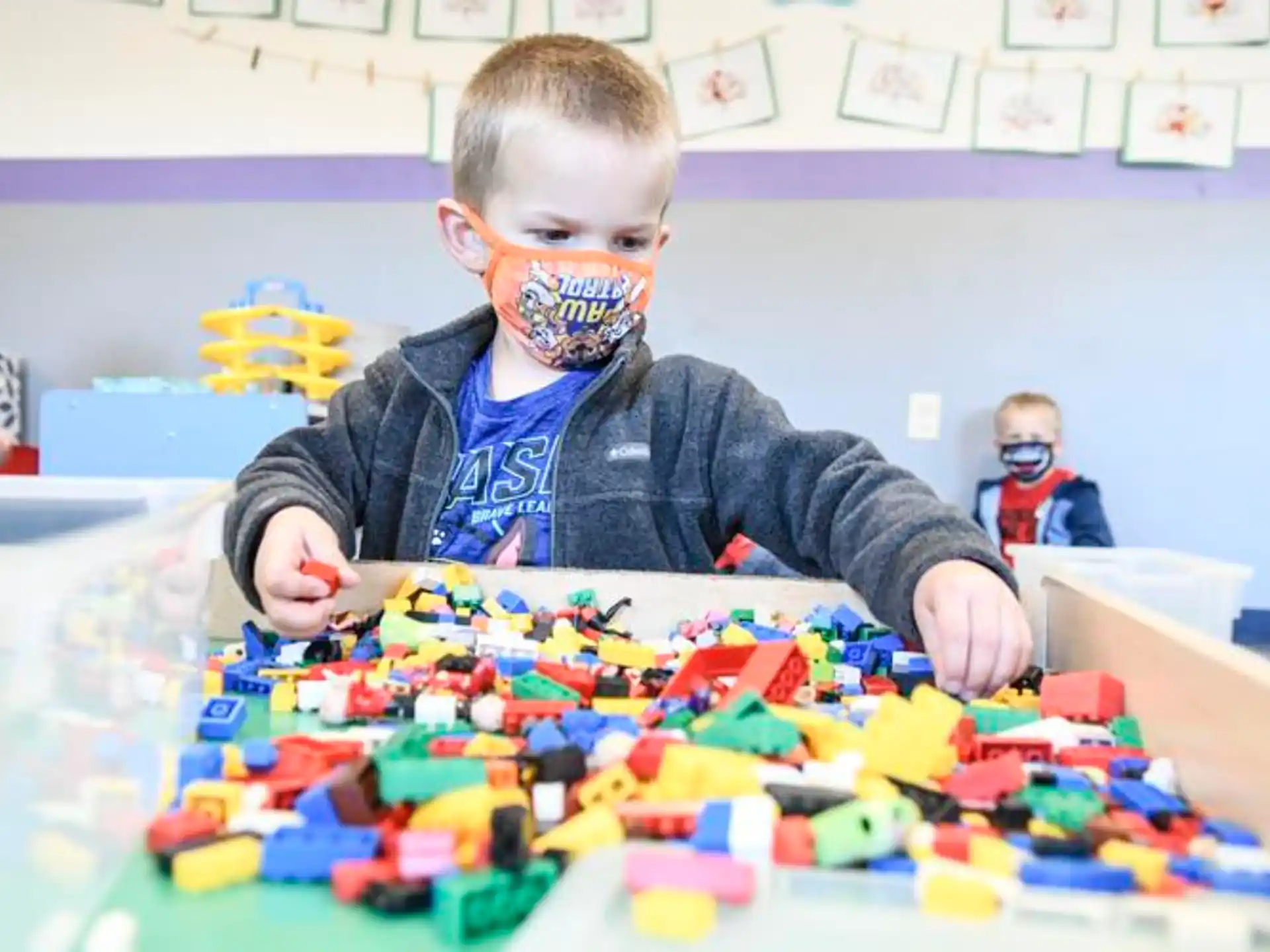 a boy with a mask on his face playing with blocks