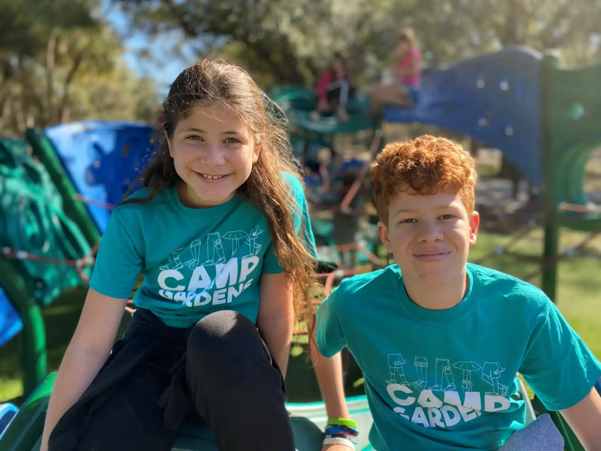 a boy and girl sitting on a playground chair