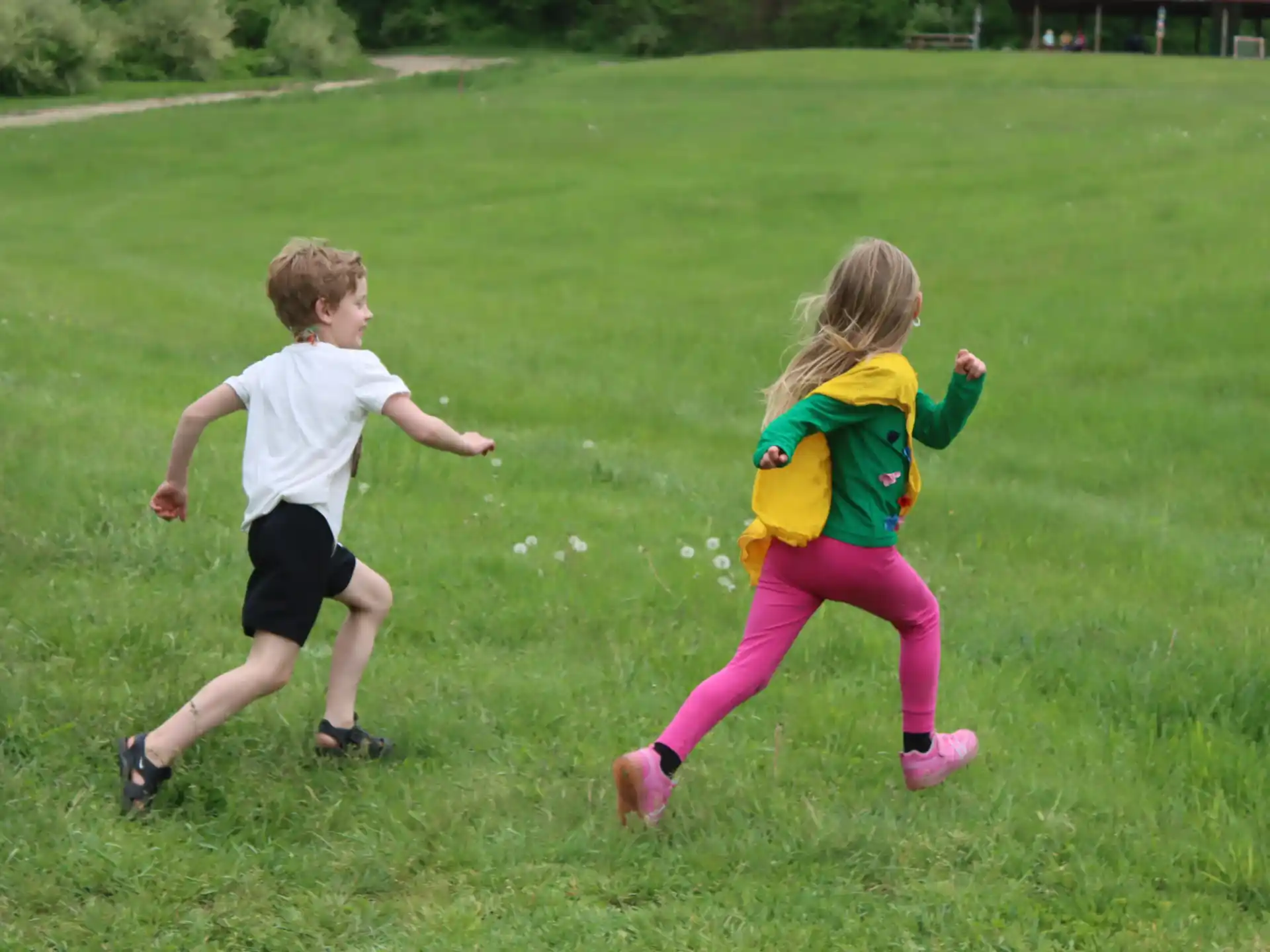 a couple children running in a grassy field