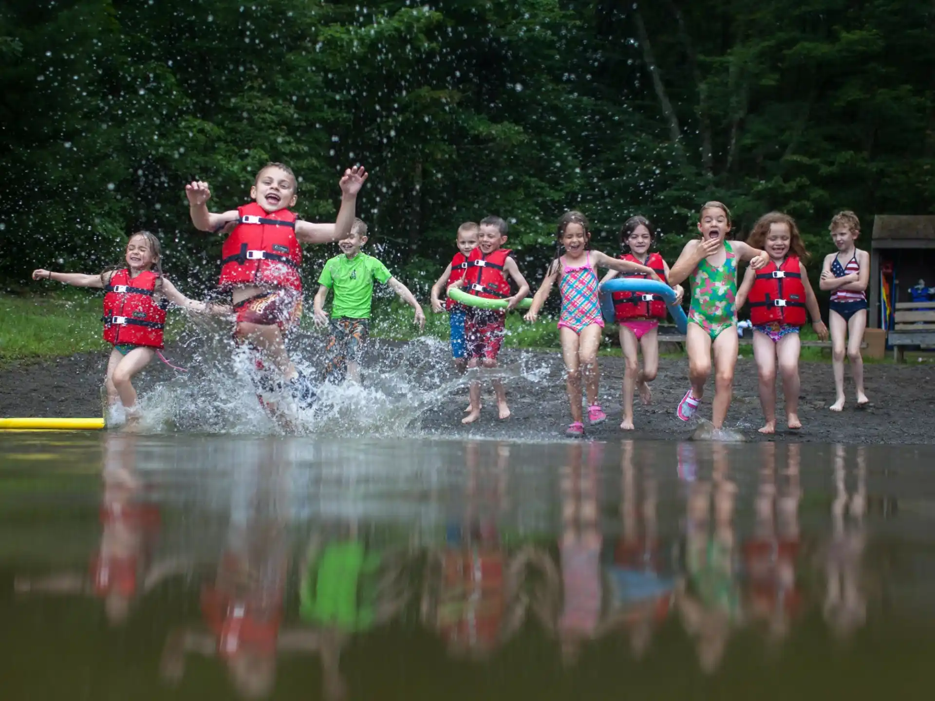a group of children jumping into a body of water