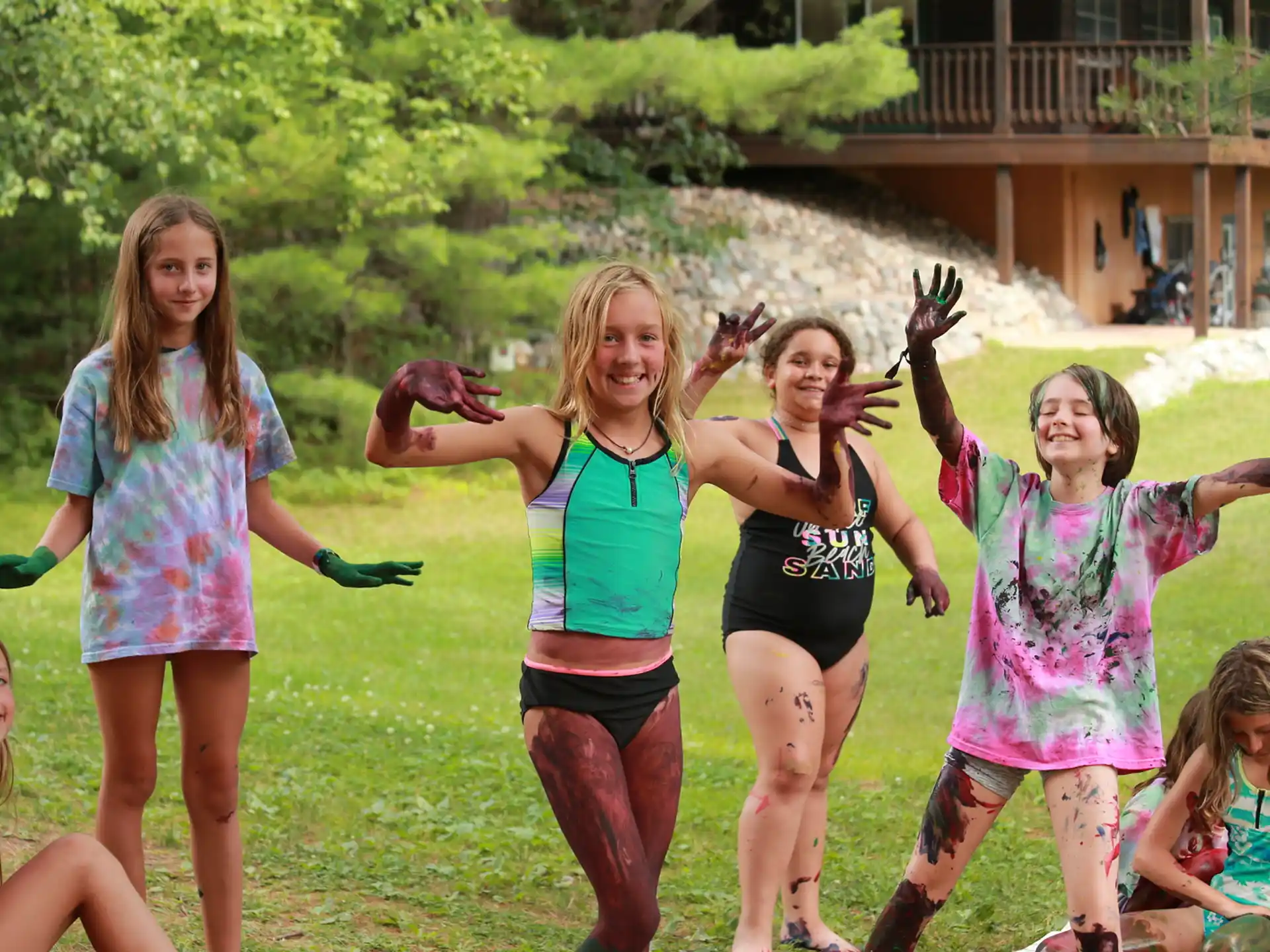 a group of girls in a grassy area with trees and a building in the background