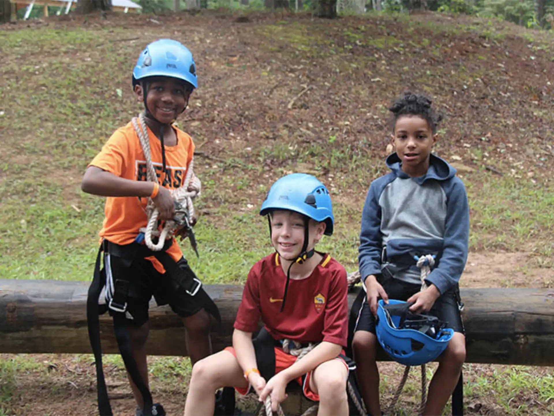 a group of kids wearing helmets and sitting on a log