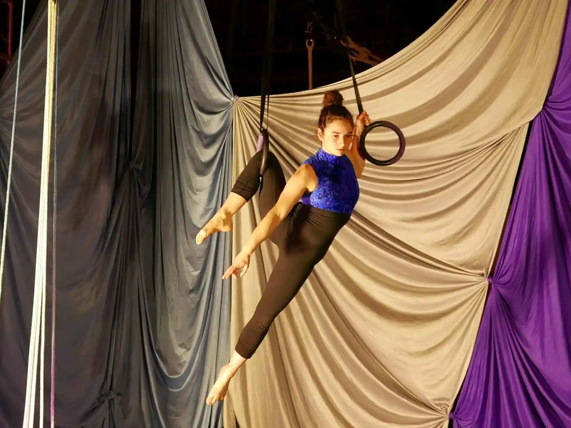 a woman in a blue top and black pants from a rope