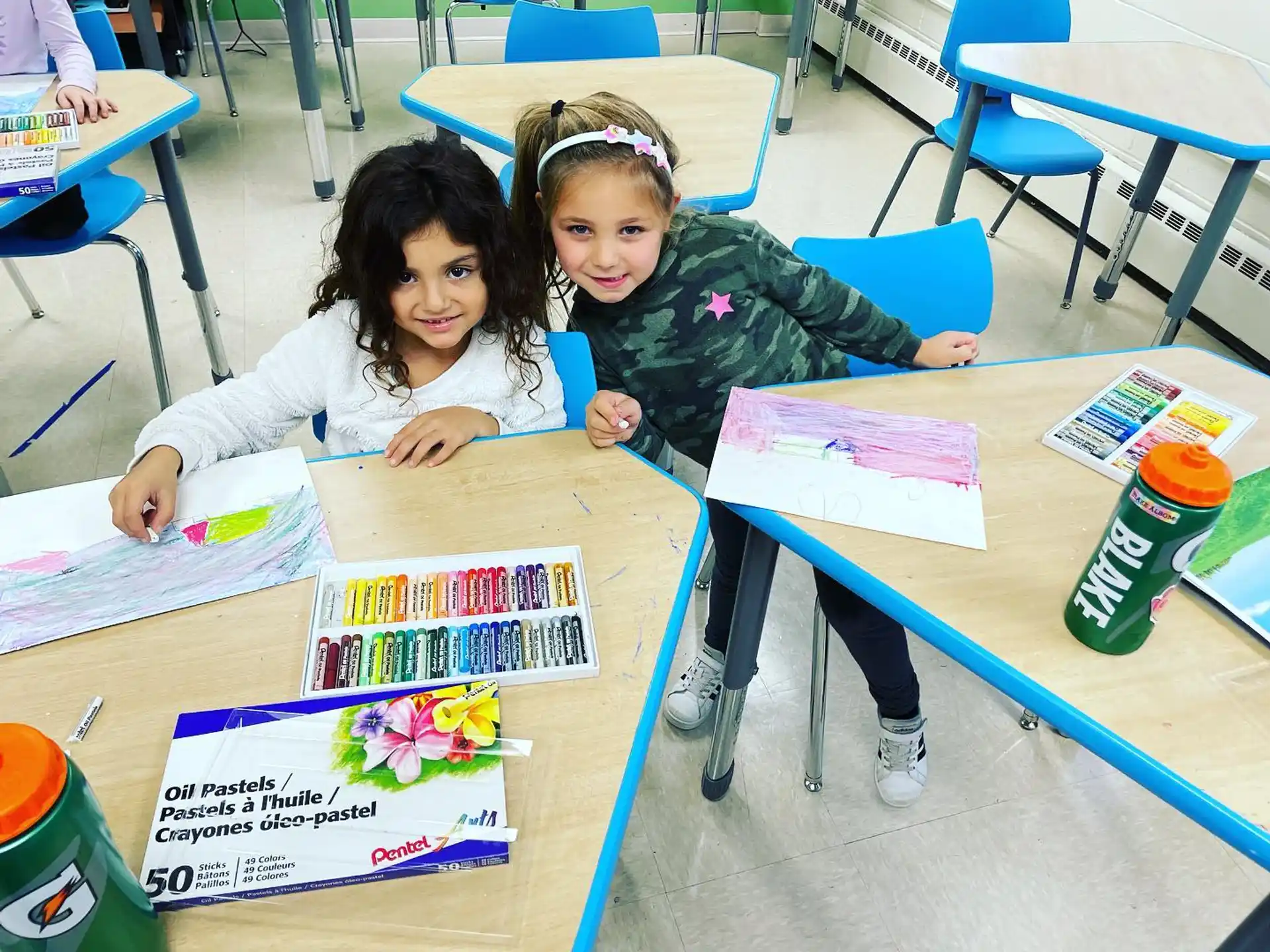 a few young girls sitting at a table with books and a book