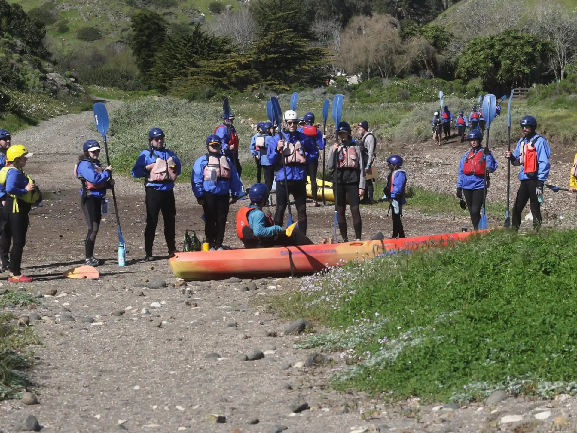 a group of people standing on a rocky area next to a body of water