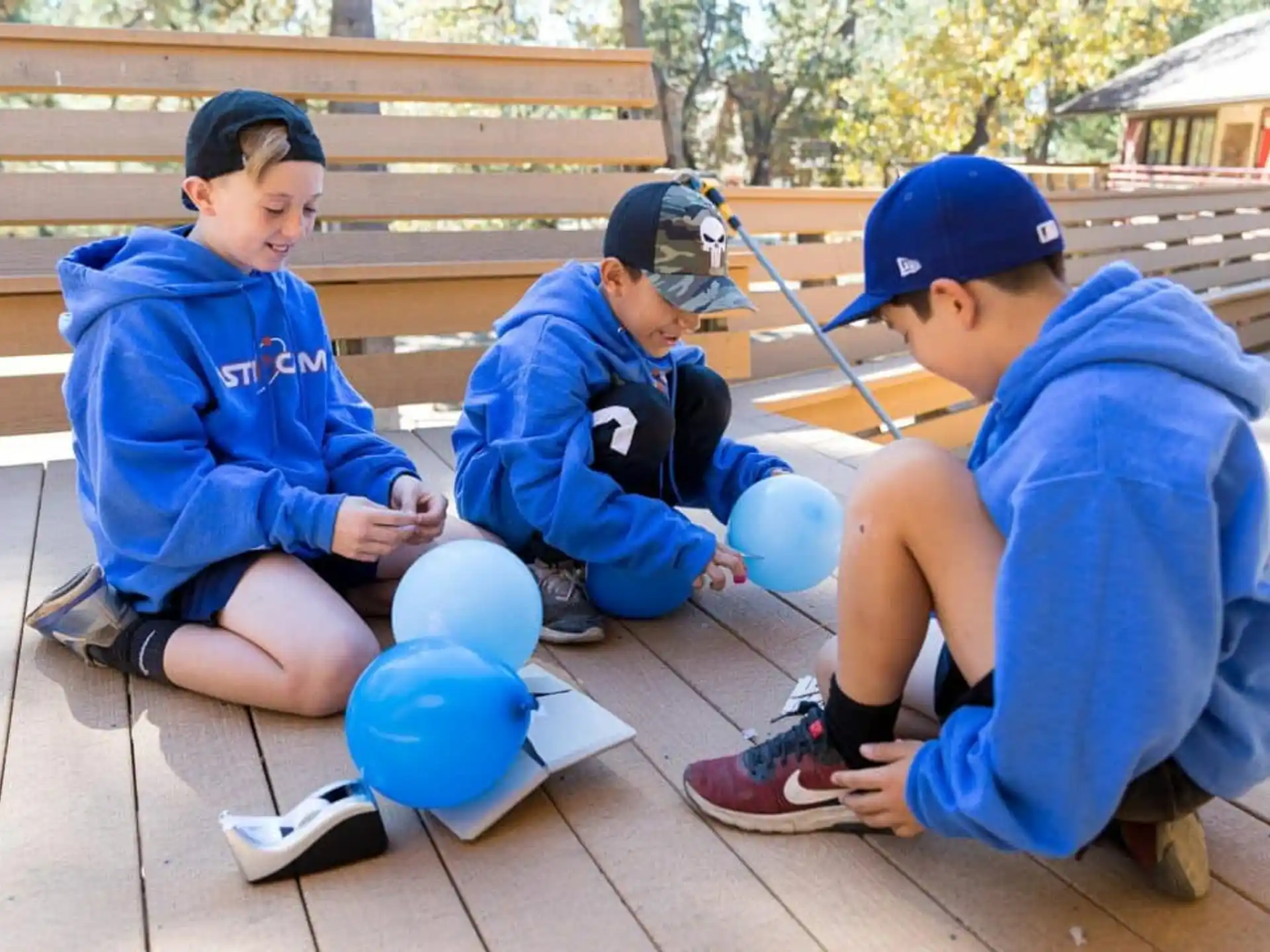 a group of boys sitting on a bench with blue balls