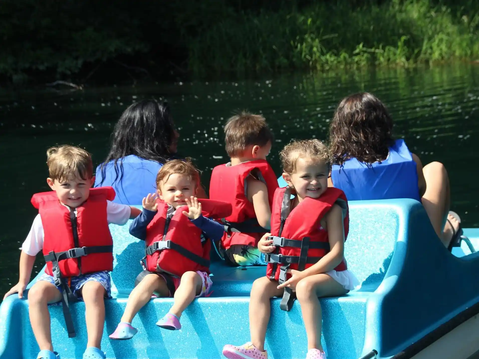 a group of kids sitting on a blue boat in the water