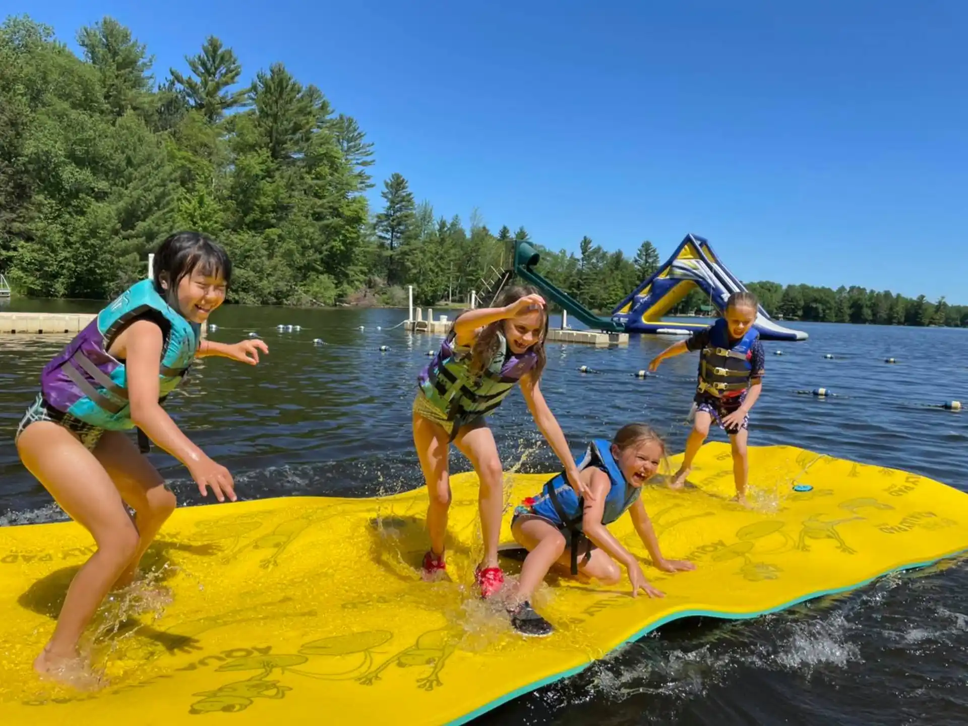 a group of kids on a yellow and blue raft in a lake