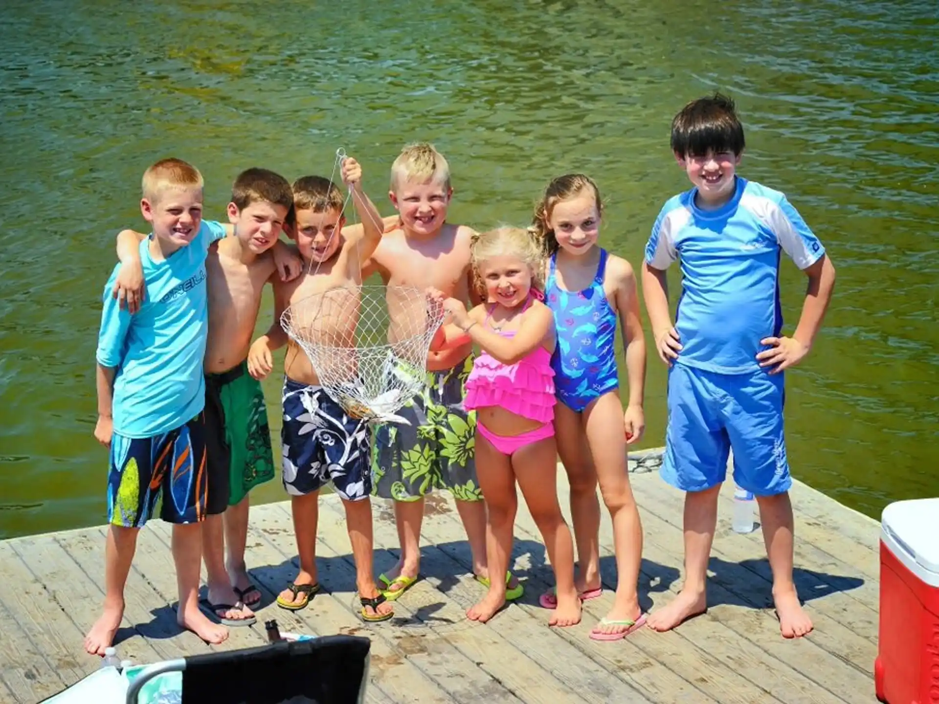 a group of children posing for a photo on a dock