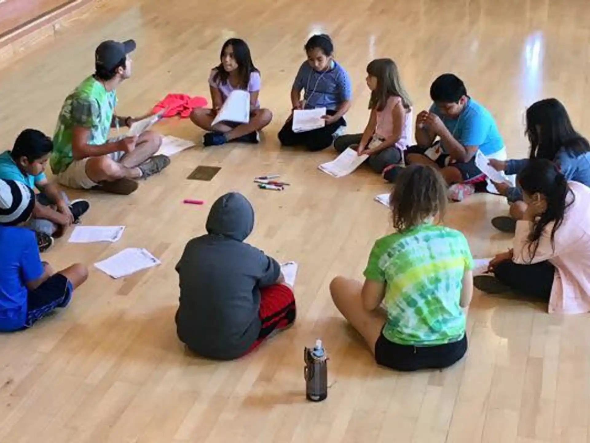 a group of people sitting on the floor writing on paper