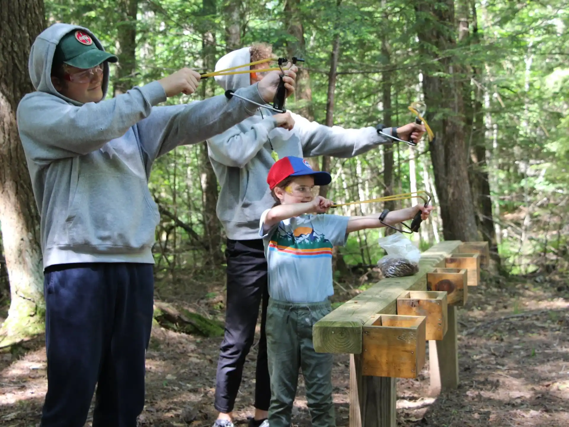 a person and a boy holding a bow and arrow in the woods