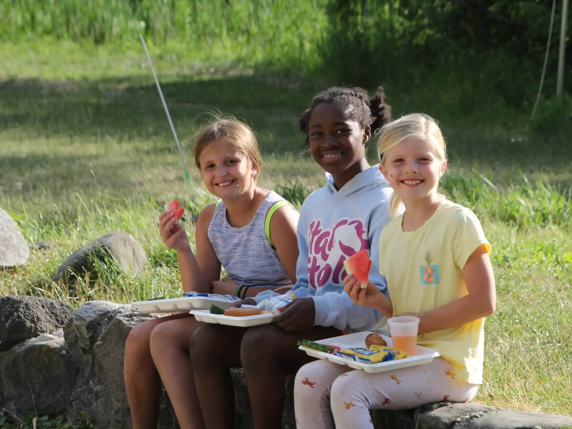a group of children sitting on a rock posing for the camera