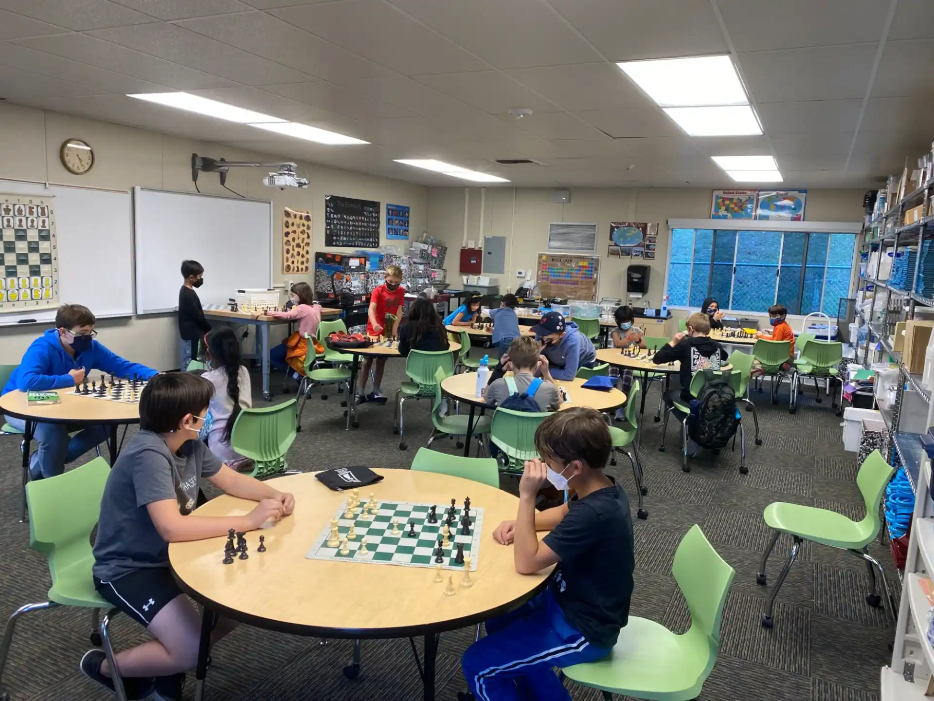 a group of people sitting at tables playing chess