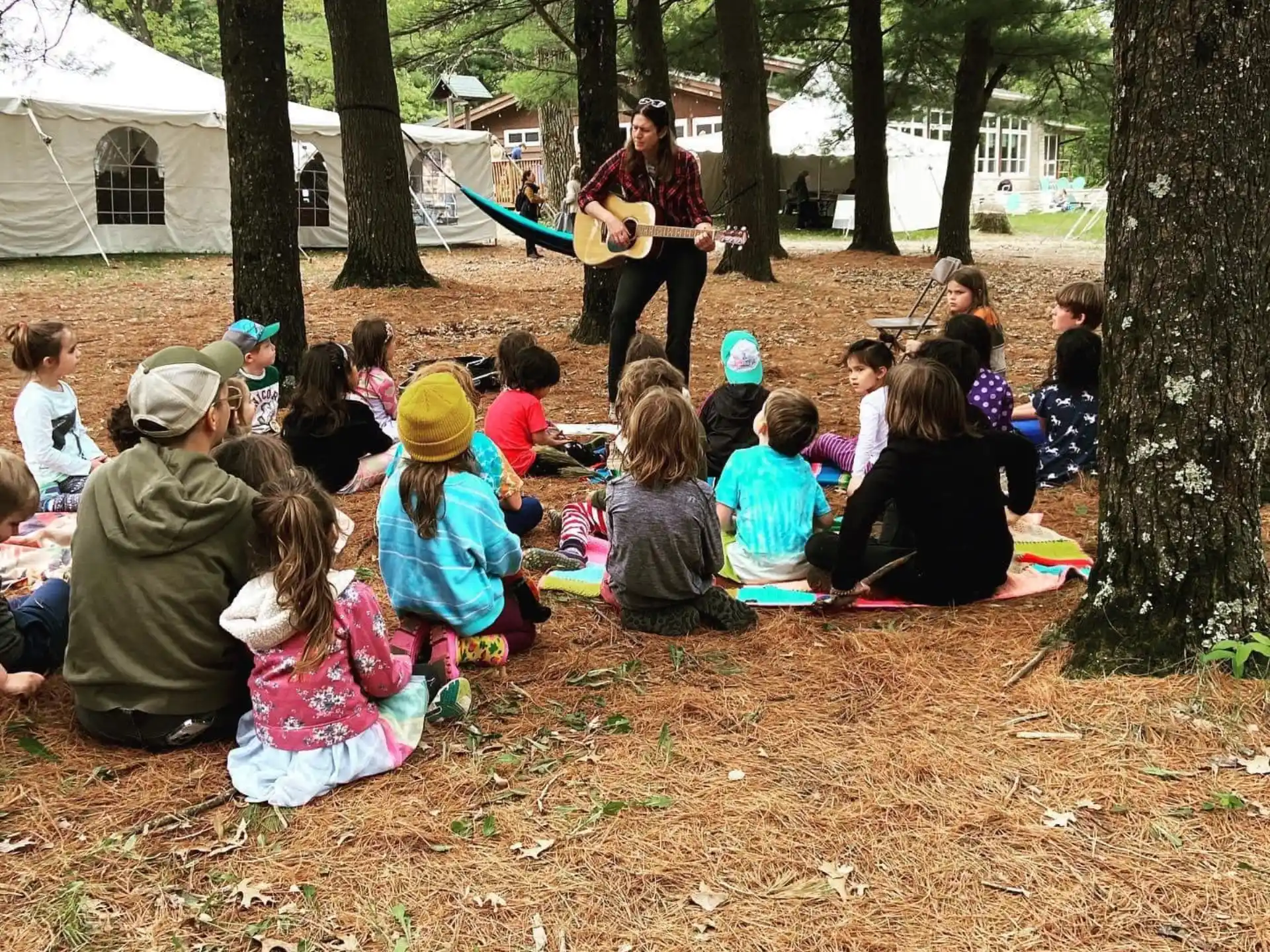 a group of people sitting on the ground watching a person play guitar