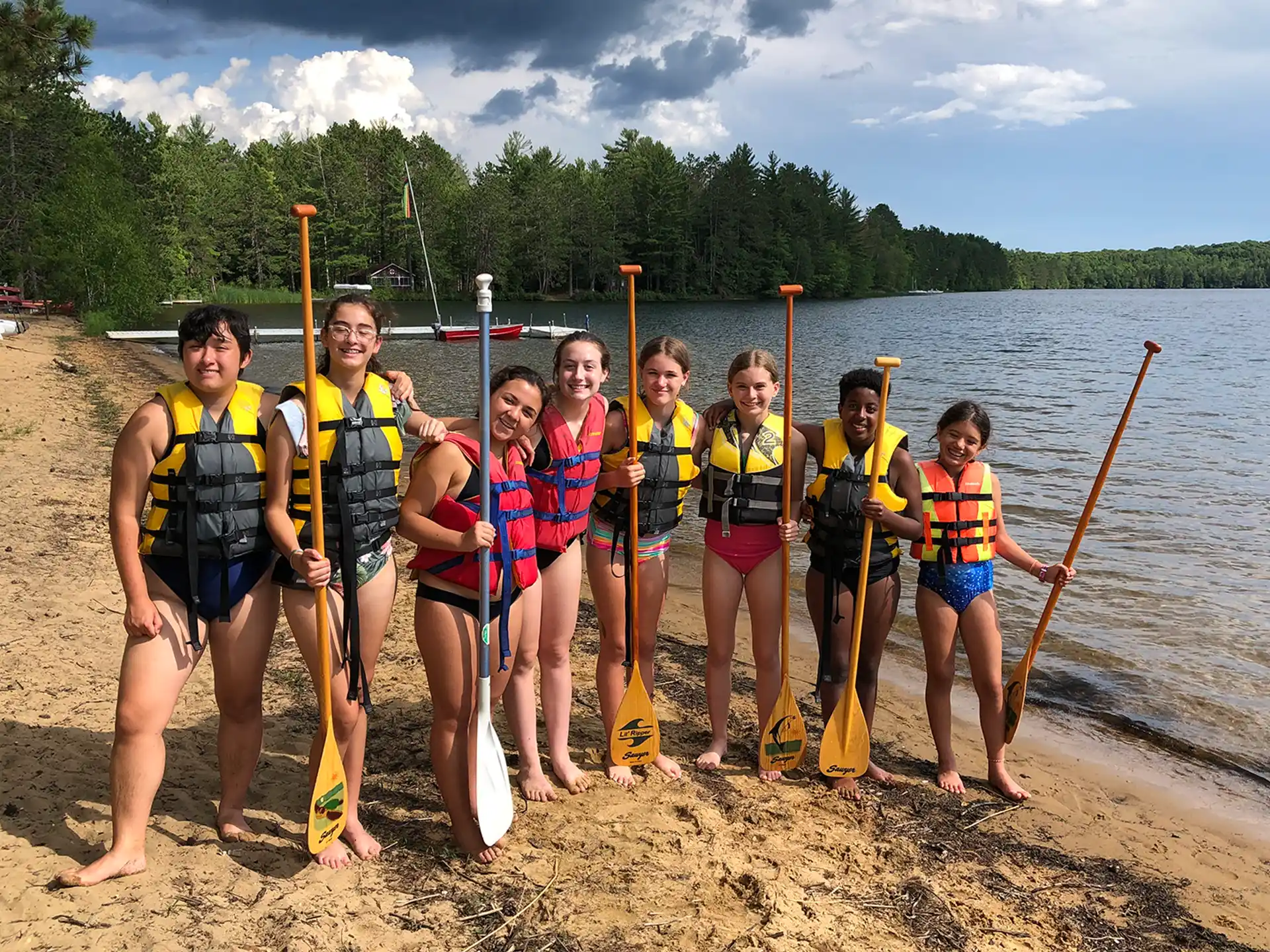 a group of people wearing life vests and standing in front of a lake