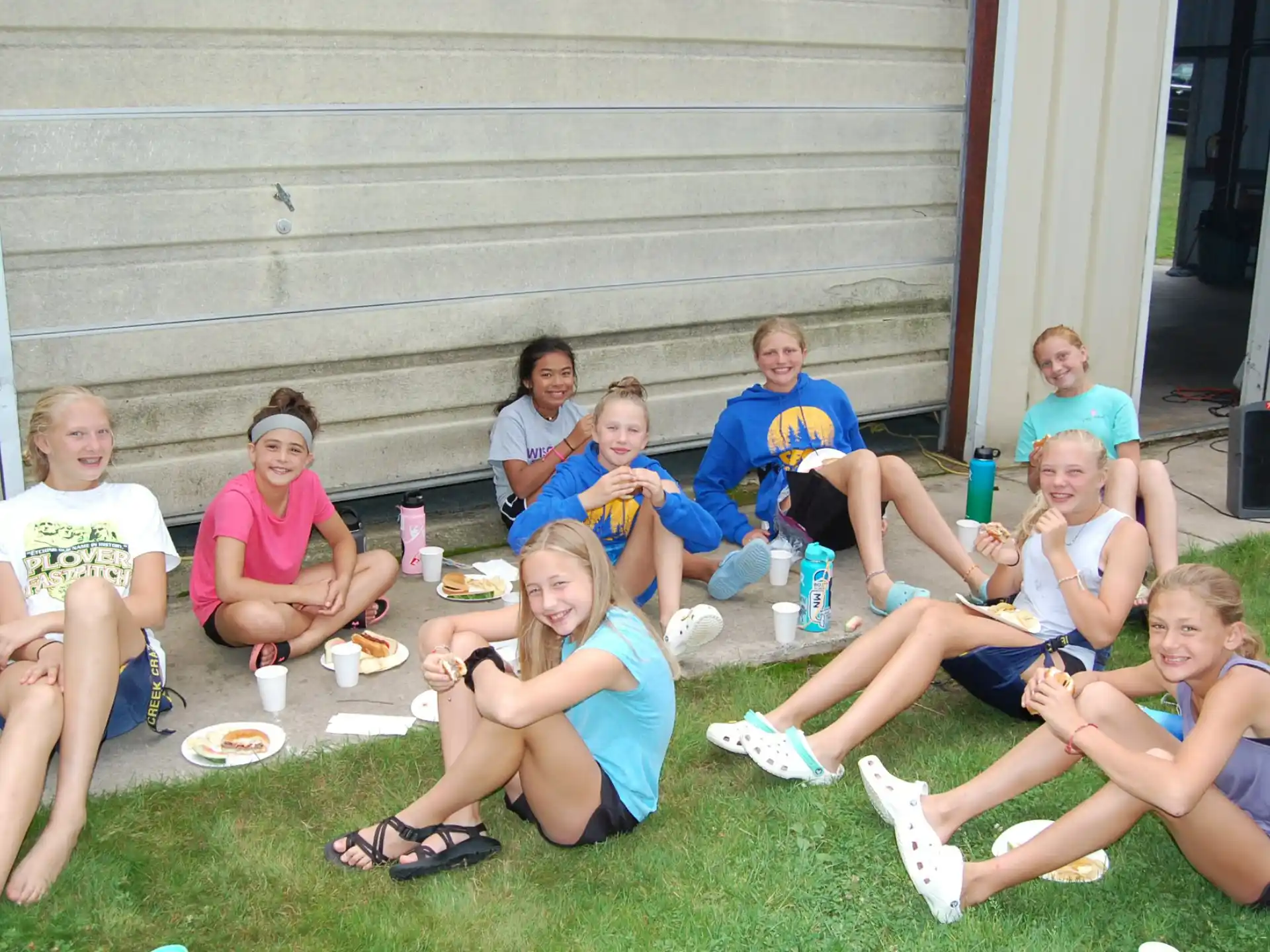 a group of people sitting on the grass eating