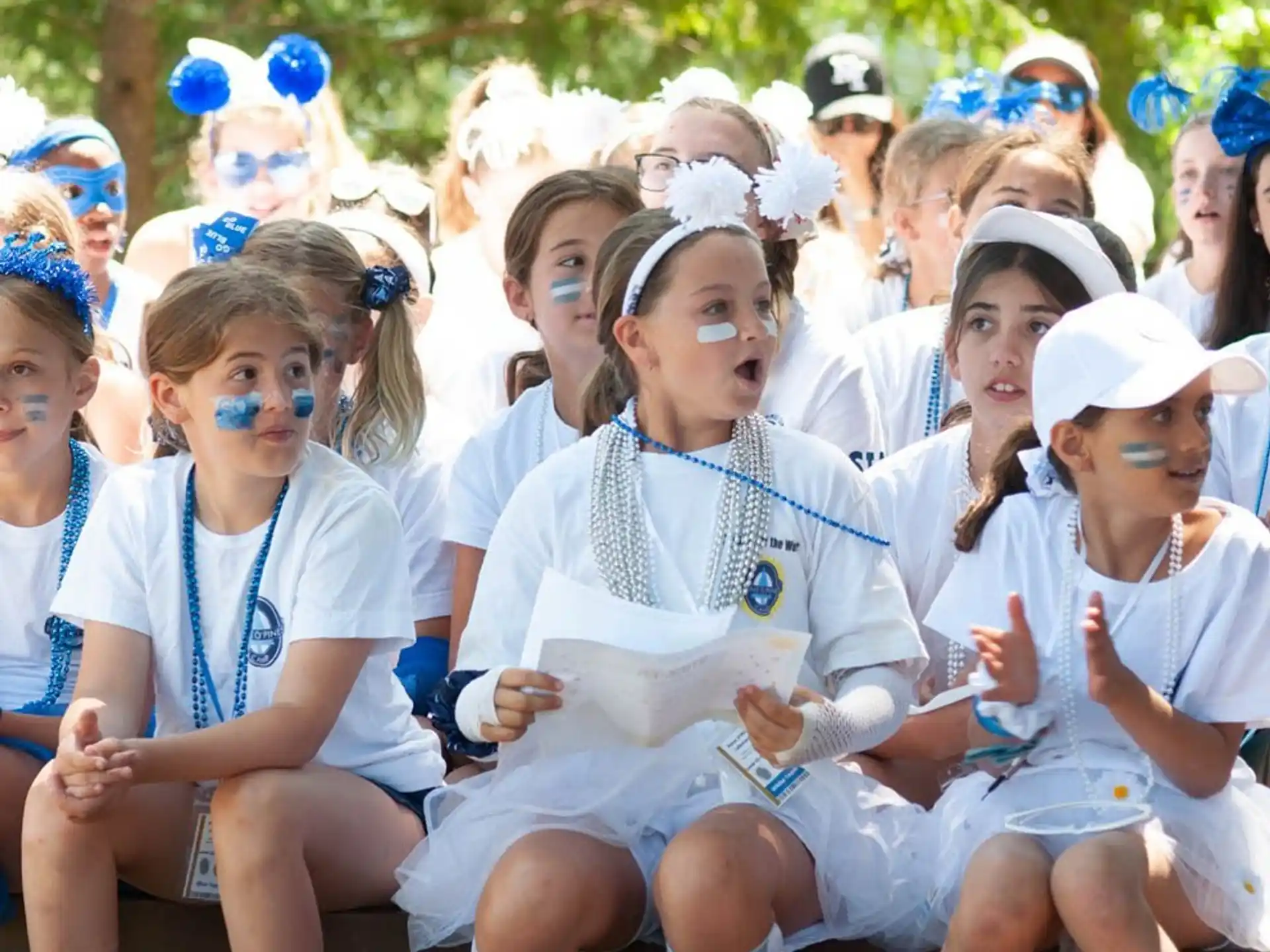 a group of girls wearing white and blue uniforms and sitting on a bench