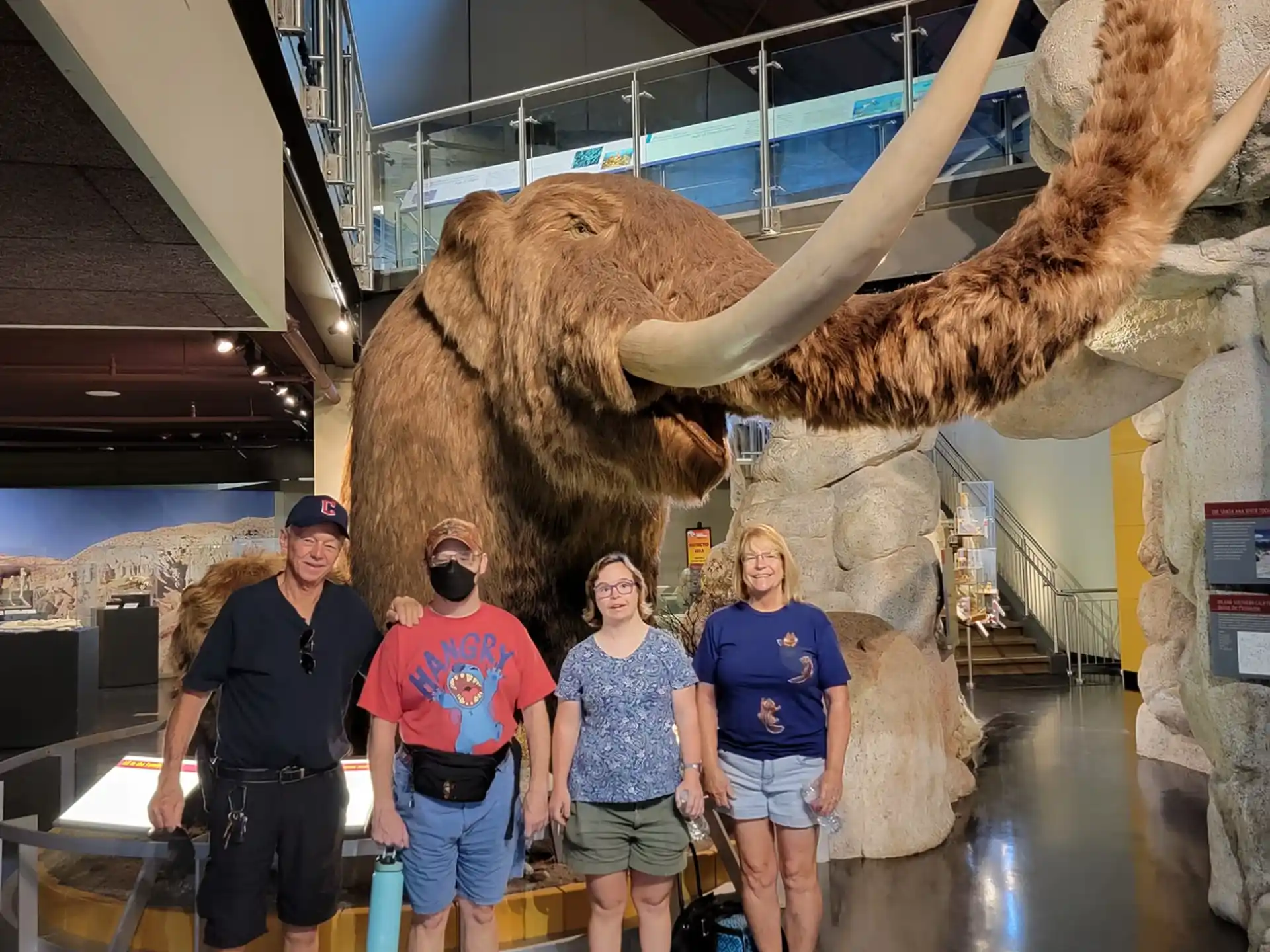 a group of people posing for a photo in front of a dinosaur skeleton