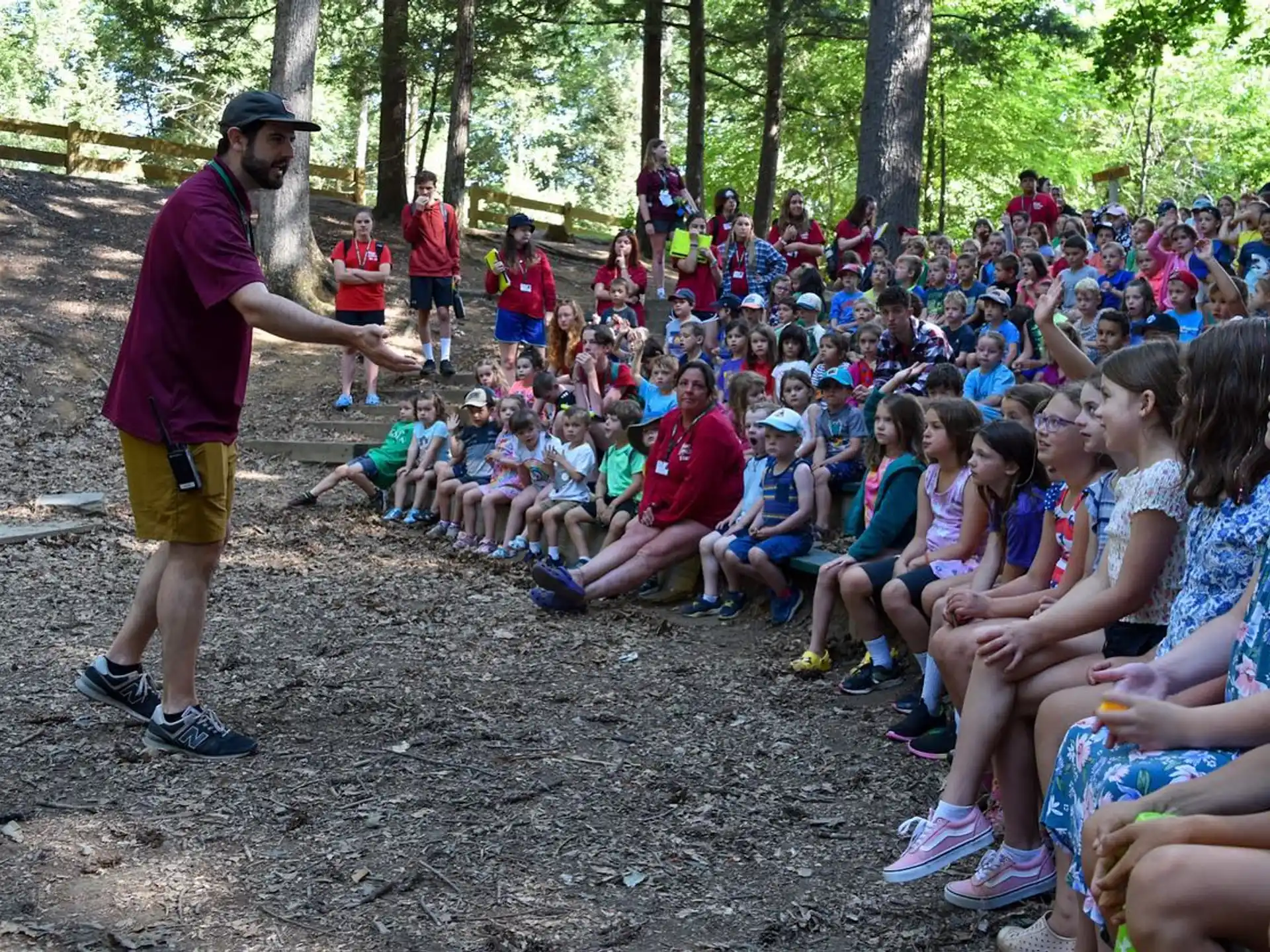 a person standing in front of a group of people sitting on the ground
