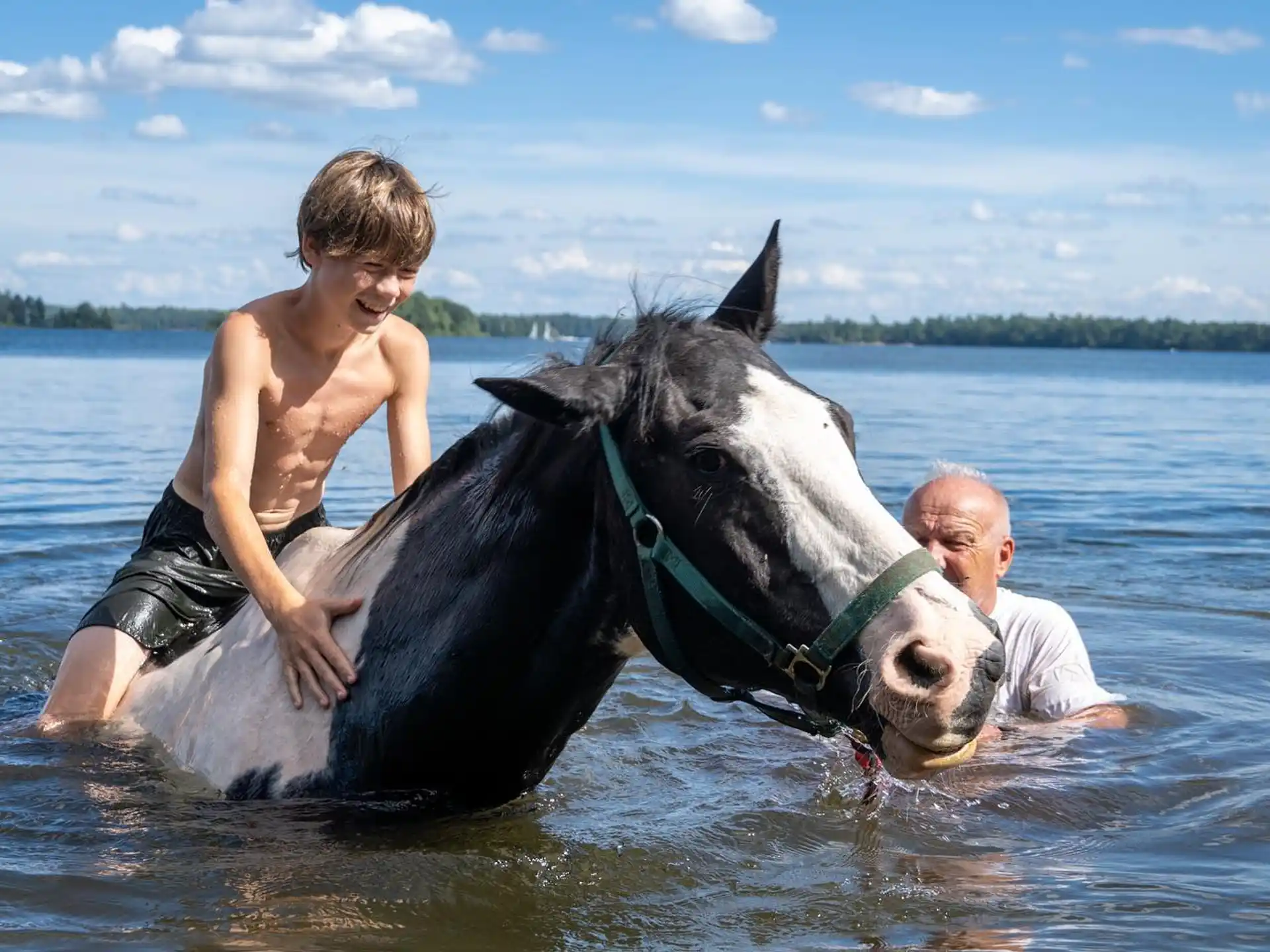 a man and a boy riding a horse in water