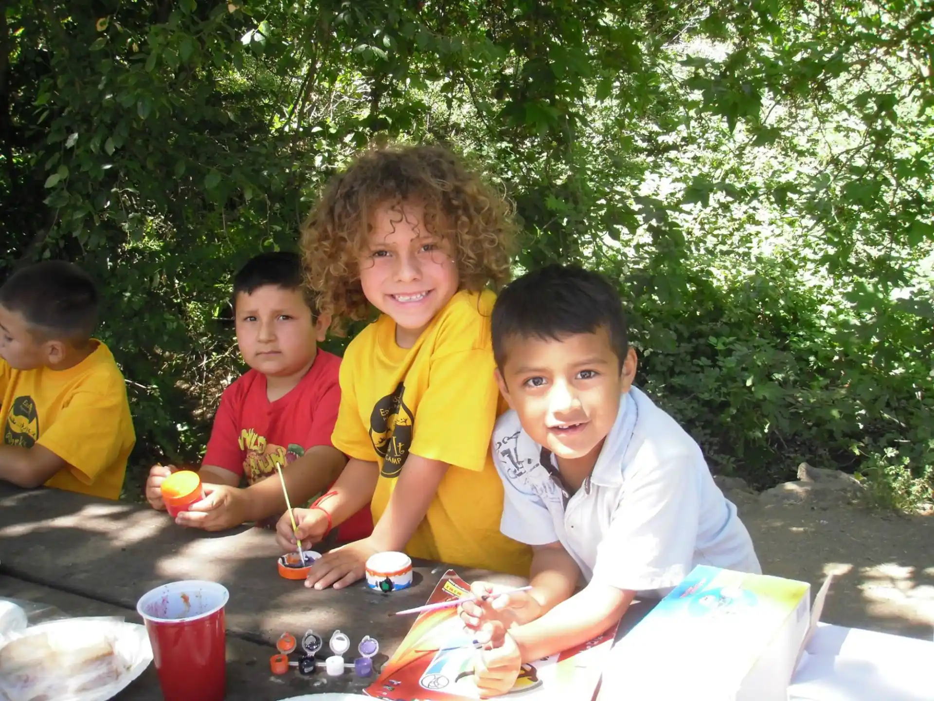 a group of children sitting at a table outside