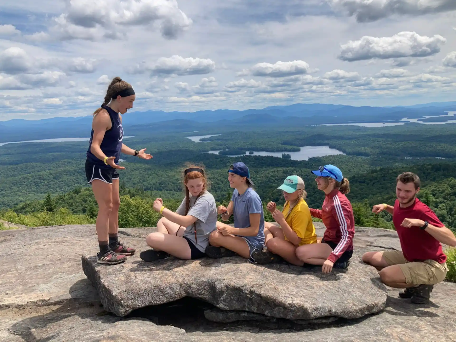 a group of people sitting on a rock overlooking a city