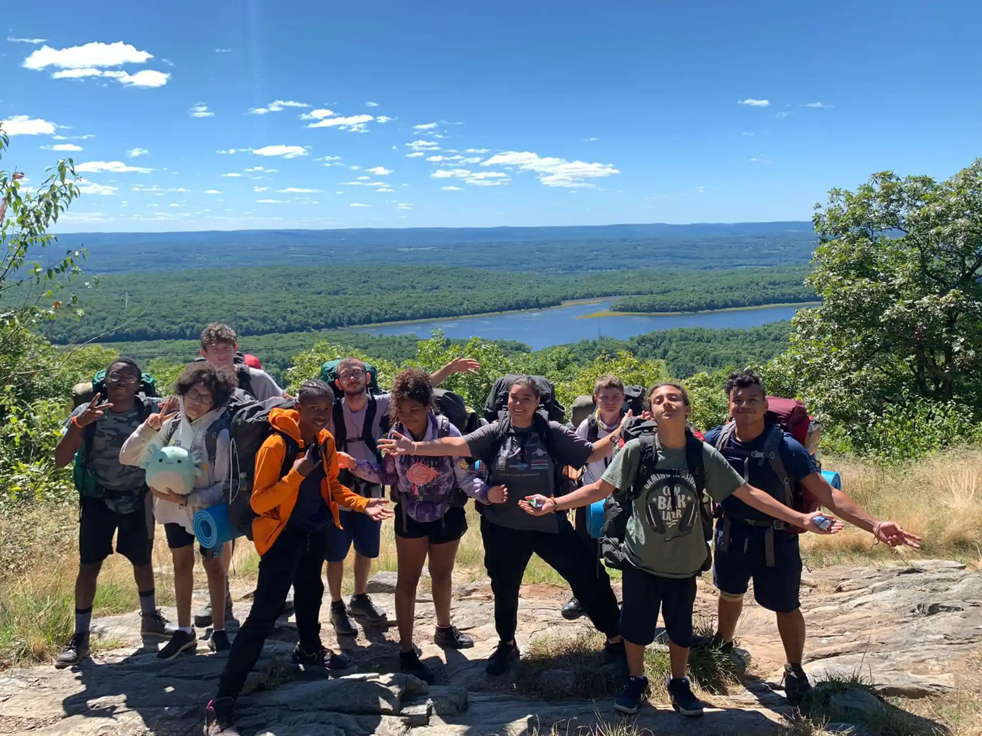 a group of people posing for a photo with a body of water in the background