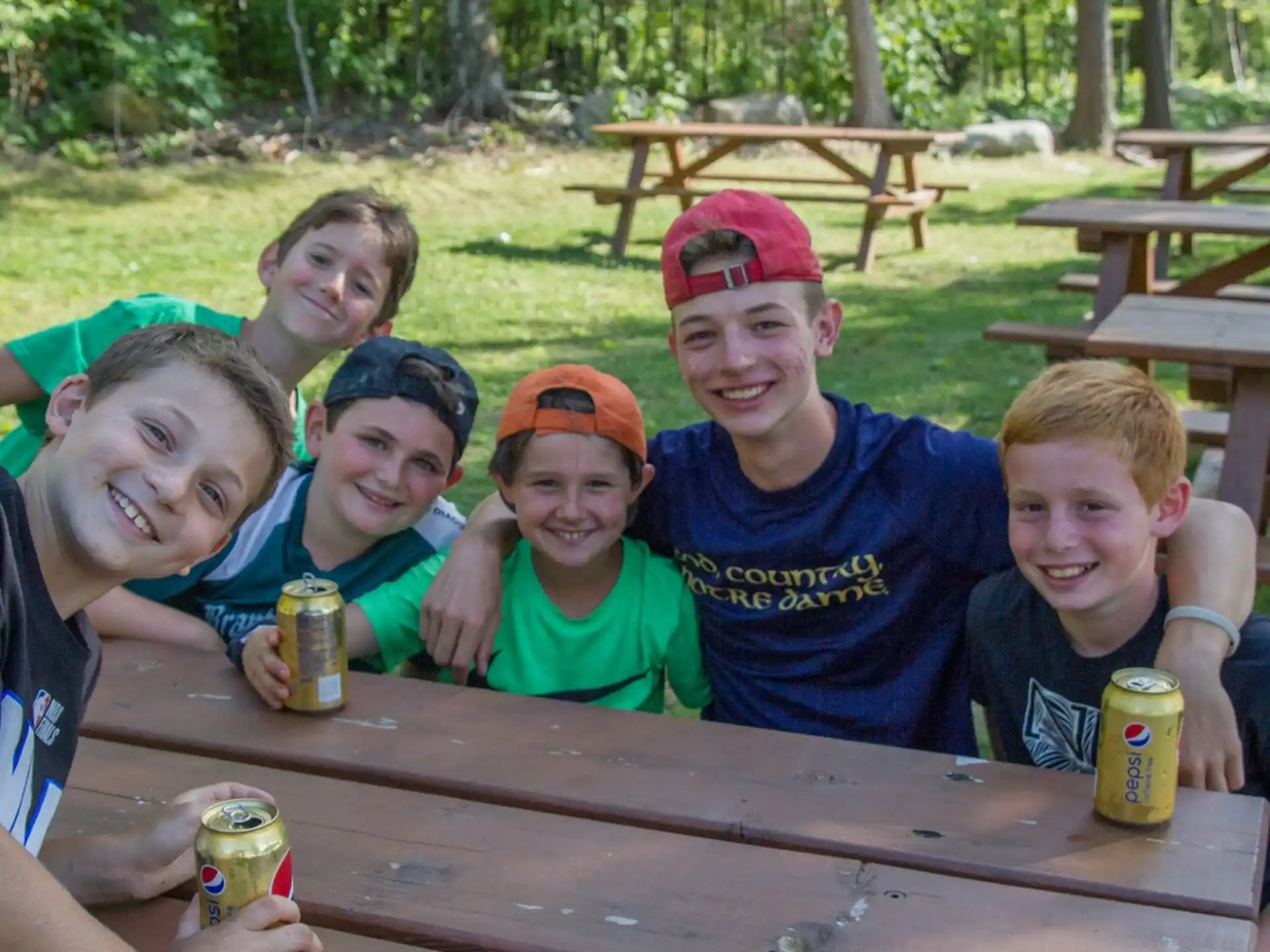 a group of boys sitting at a picnic table with cans of beer